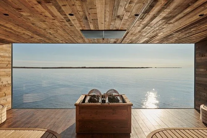 A wooden sauna with a large window looking out over the sea